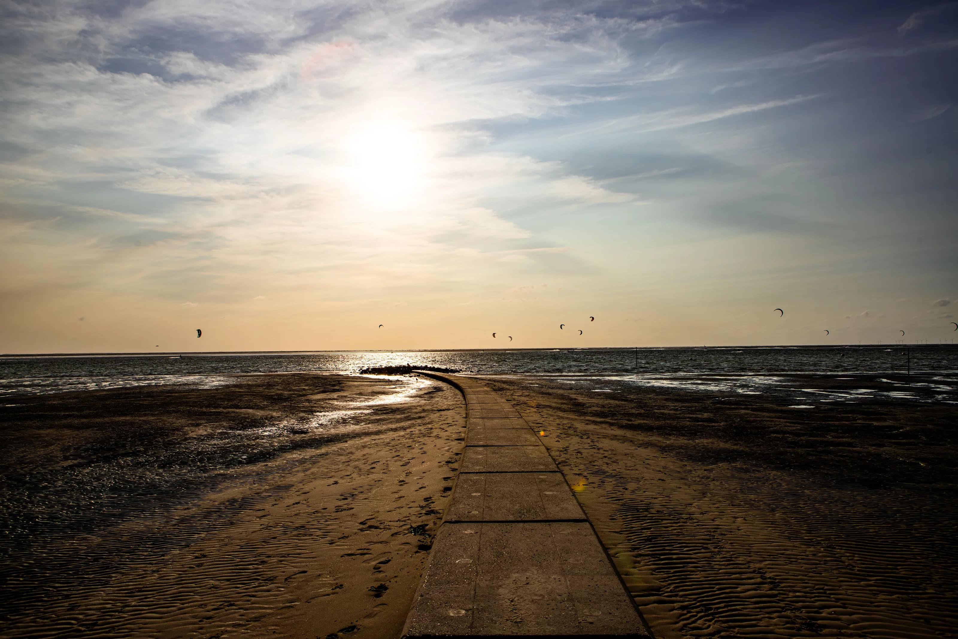 Sun above the North Sea and a curved beach path on Borkum